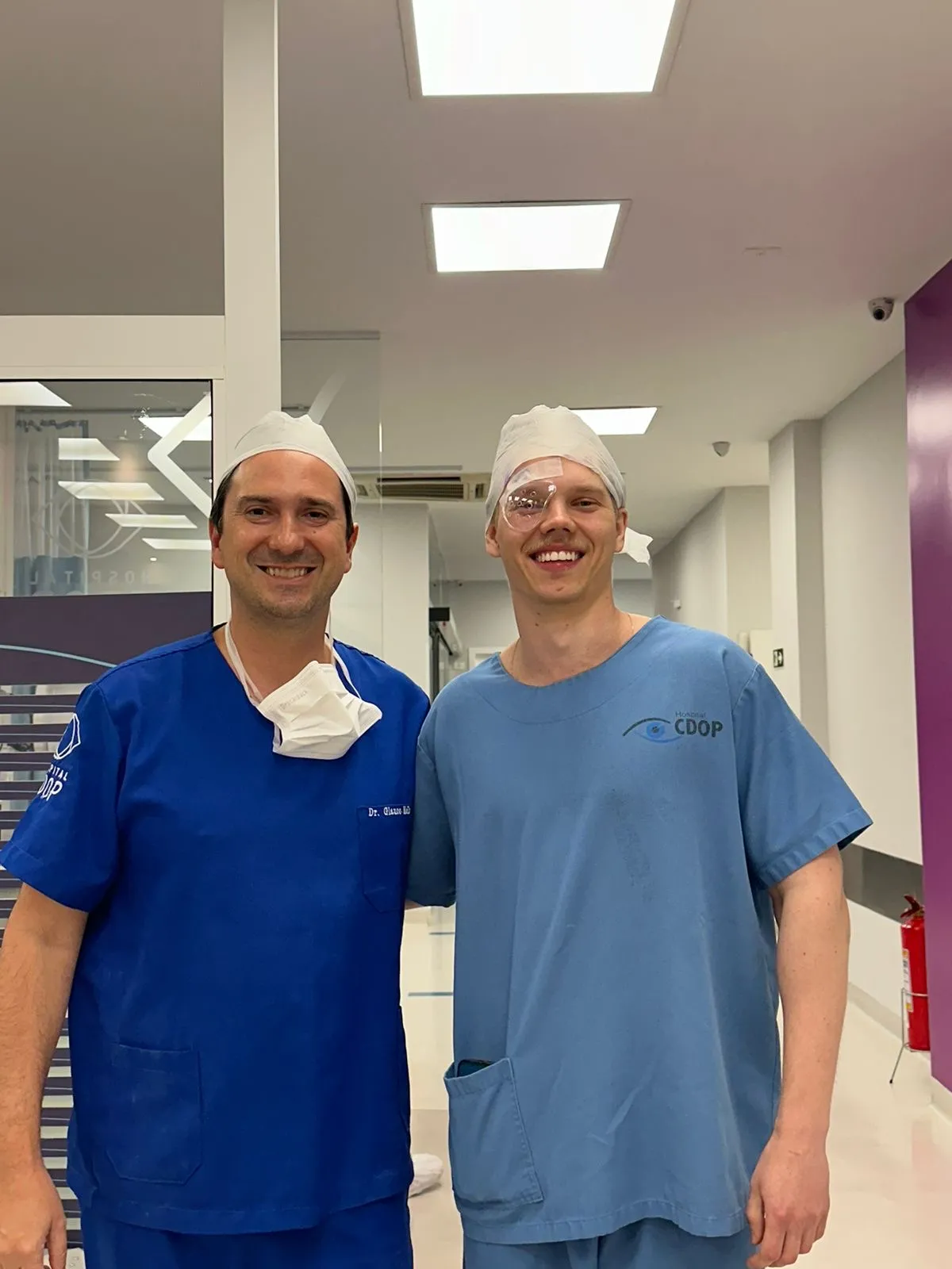 O Dr. Nicholas, de avental cirúrgico e com um protetor transparente sobre o olho direito, ao lado do Dr. Glauco Mello, no dia da própria cirurgia refrativa.